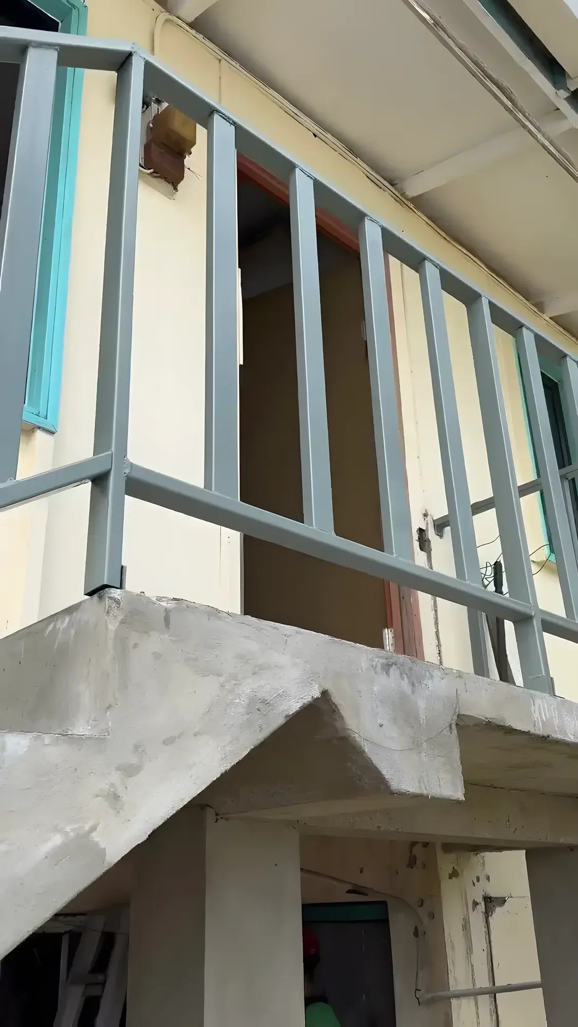 New steel handrails, painted grey-blue, fitted to the upper-floor walkway of the school building.