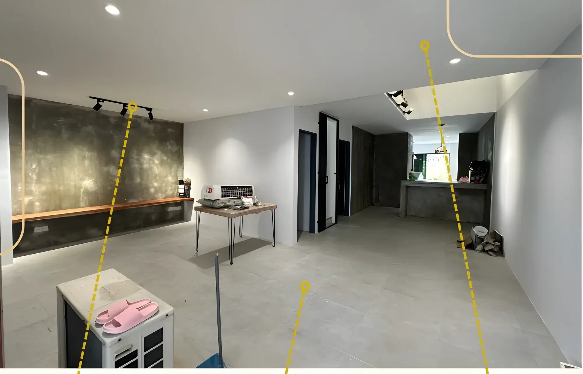 Open living area with large-format floor tiles, plaster ceiling, track lighting and a skim-coat feature wall.