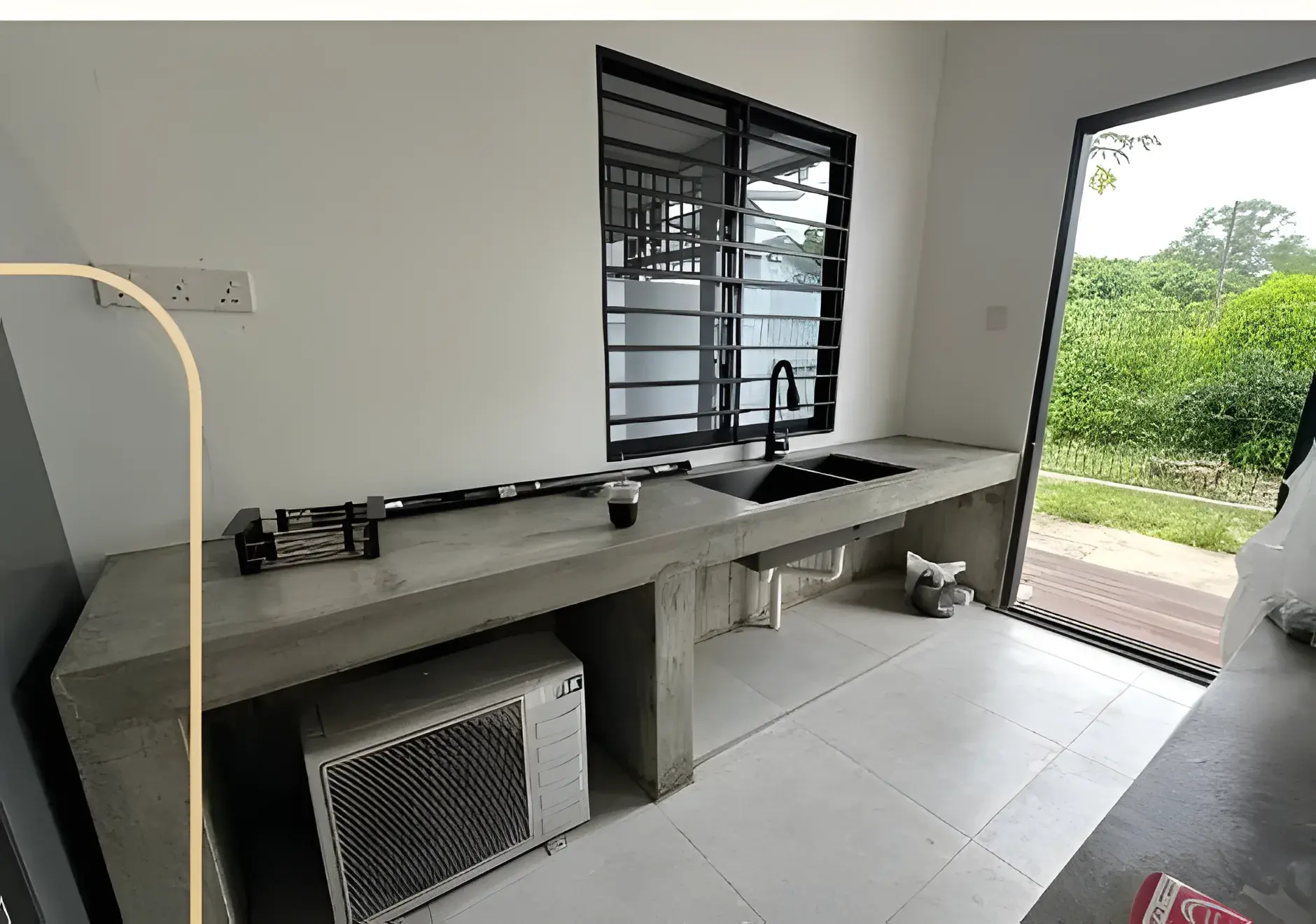 Outdoor concrete sink counter with the air-conditioning condenser tucked below.