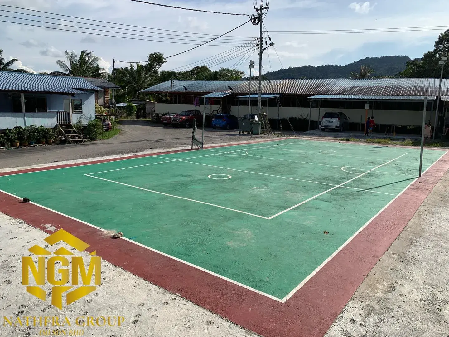 The finished multipurpose court at Kampung Kangka: green playing surface, red surround and white lines.