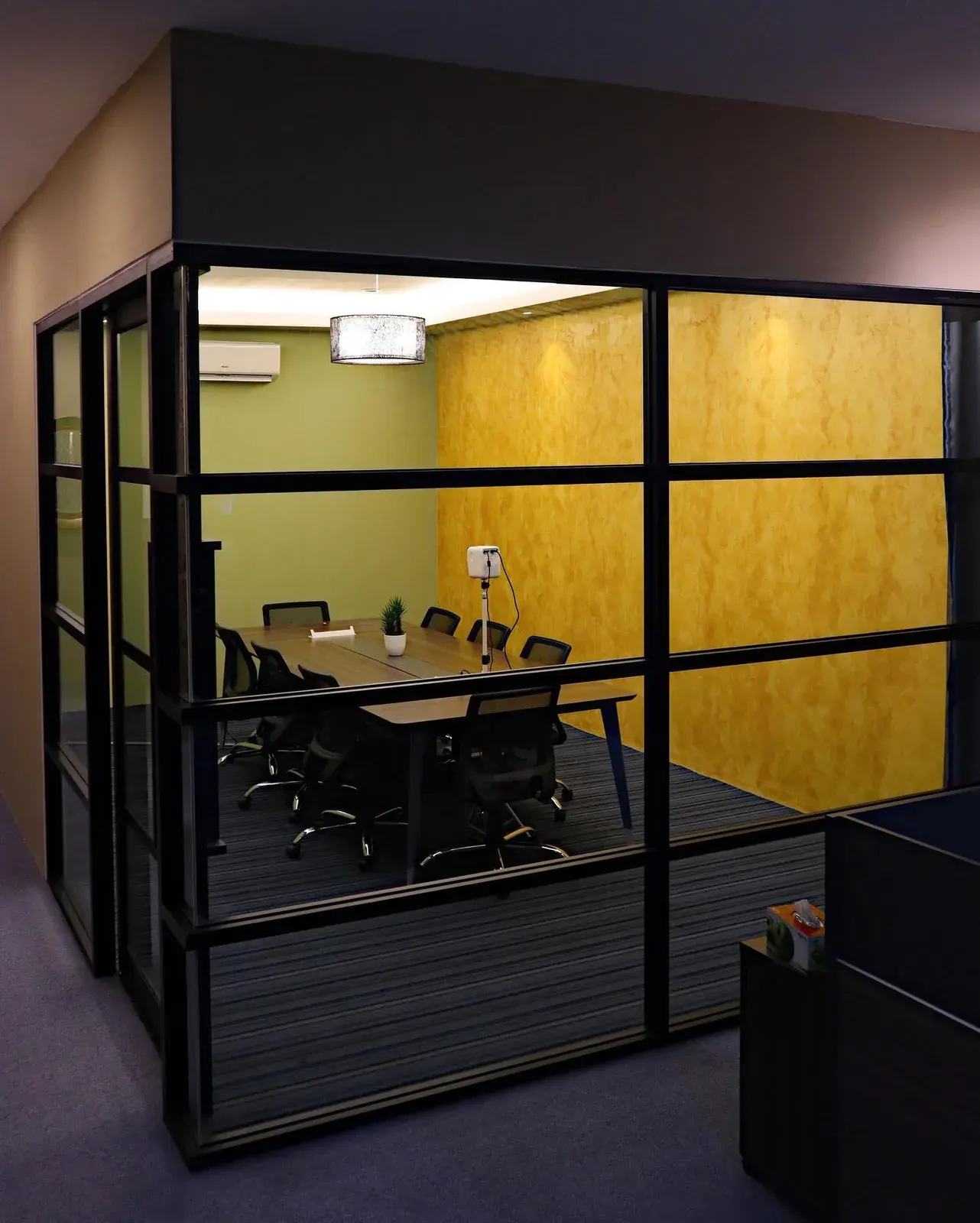 The glazed meeting room, black steel frames and a long table.