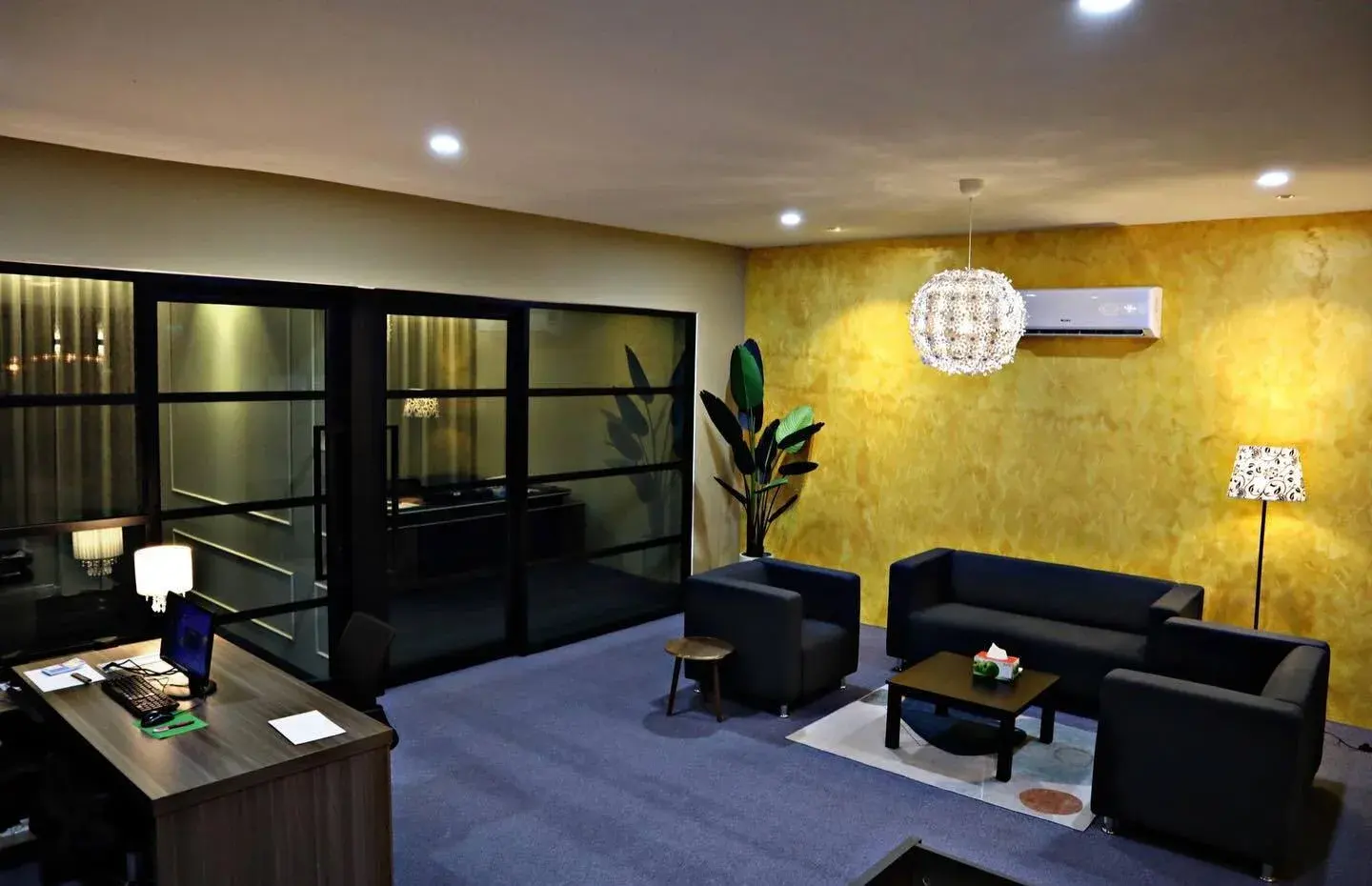 Reception and workspace with a glazed meeting room, gold textured wall and dark blue carpet.
